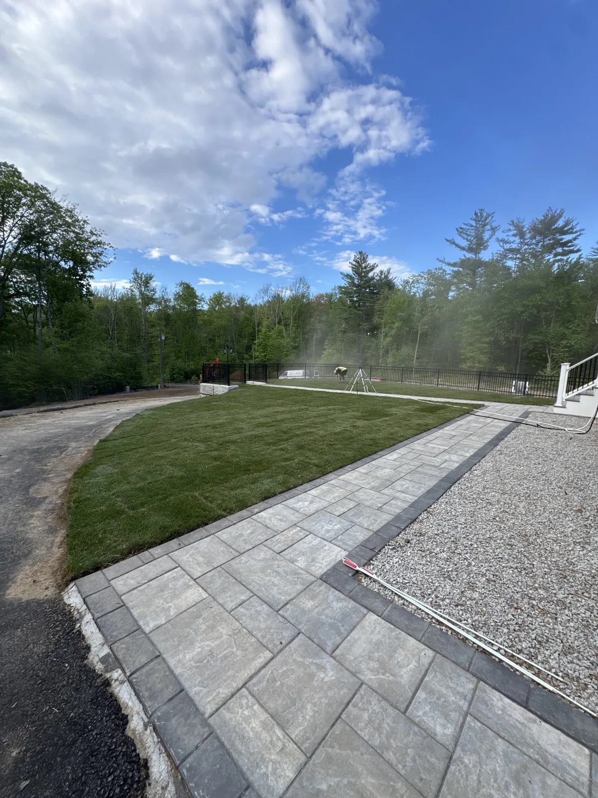 Freshly-laid Kentucky Bluegrass sod beside paver walkway with sprinkler watering — Millbury MA Worcester County sod installation