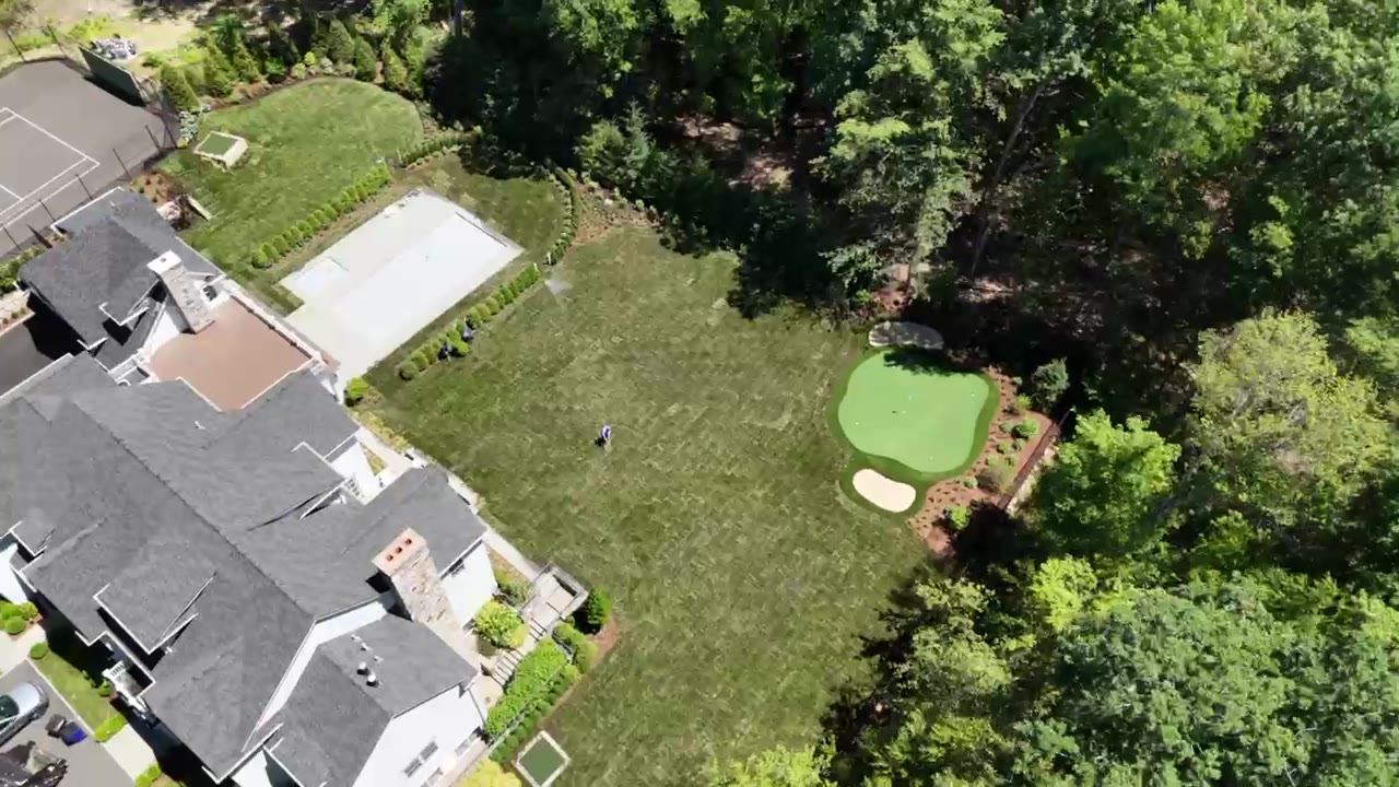 Drone fly-over of a New Canaan, CT estate after sod installation — freshly laid sod across the lawn around the pool and putting green